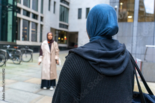 Two women wearing hijabs meeting in street photo