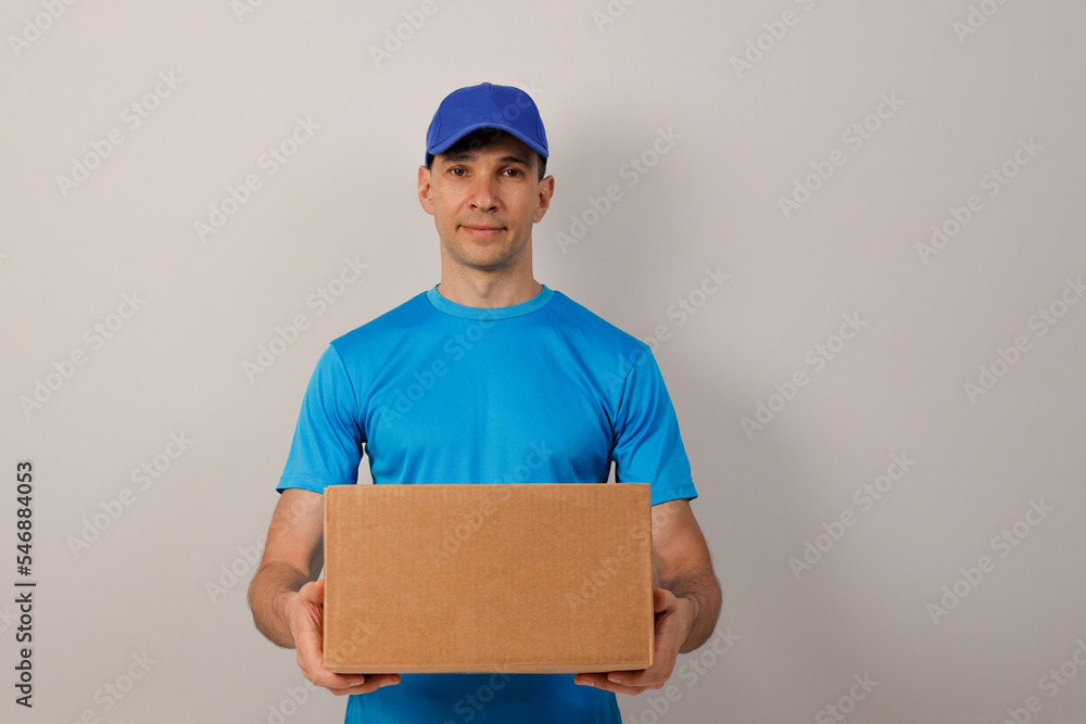 Portrait of handsome attractive cheerful delivery man holding card-board box. Express delivery service. Copy space. Portrait of handsome attractive cheerful delivery man holding card-board box. Express delivery service. Copy space.