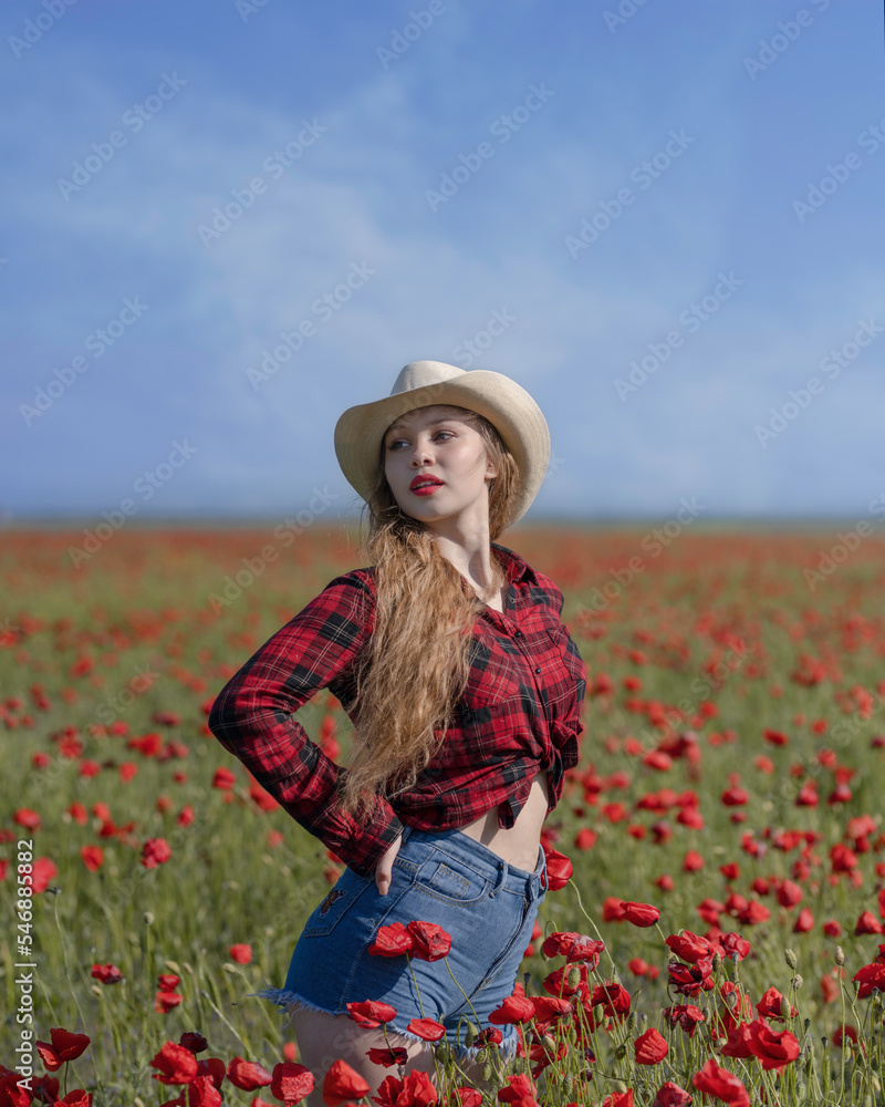 Obraz premium Blonde girl in a cowboy hat among poppy fields