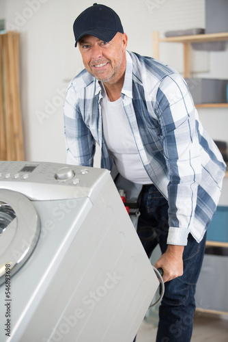 mature man moving washing machine on pallet truck