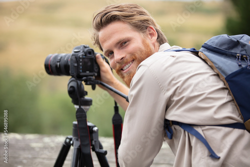 male photographer in the countryside using camera on tripod