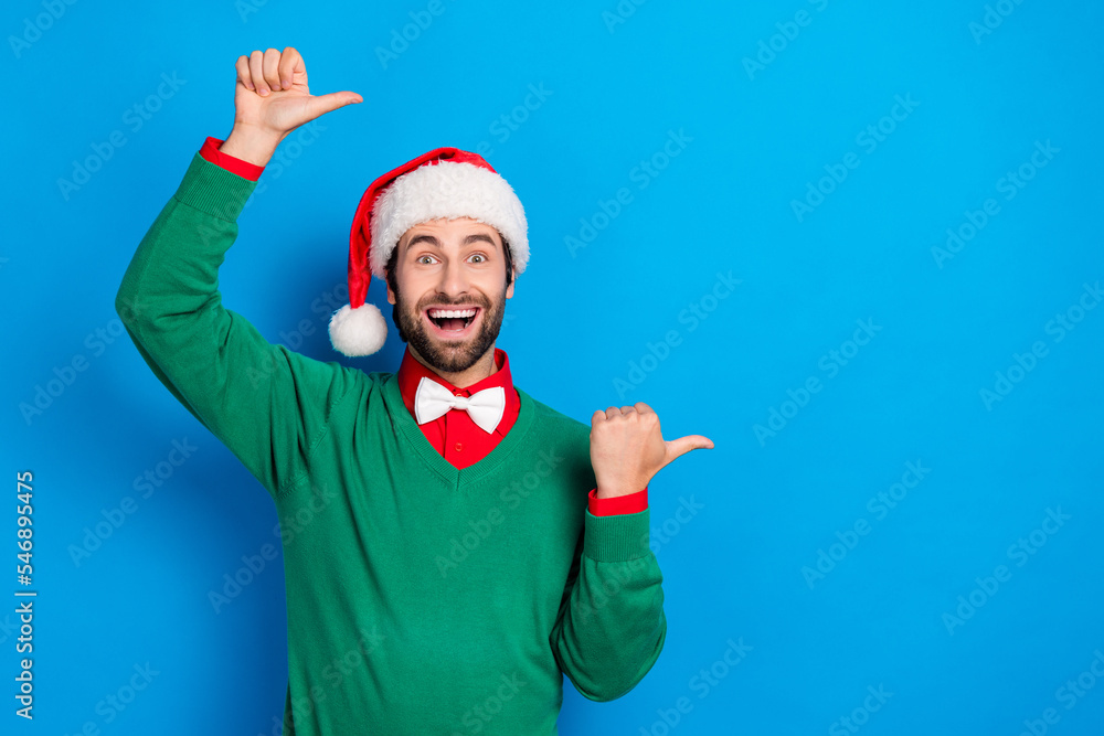 Photo of excited crazy handsome guy direct thumb fingers empty space offer isolated on blue color background Photo of excited crazy handsome guy direct thumb fingers empty space offer isolated on blue color background