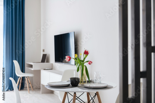 a table with flowers, a TV and blue curtains in a new house