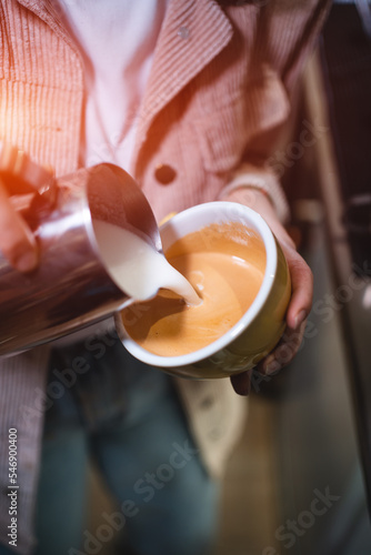 barista making fresh tasty cappuccino or latte coffee with hot milk, restaurant