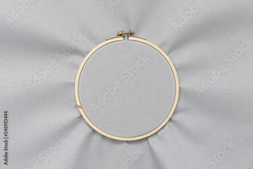 Grey blank canvas on wooden round frame as a background. Wooden hoop for embroidery. Hobby concept.