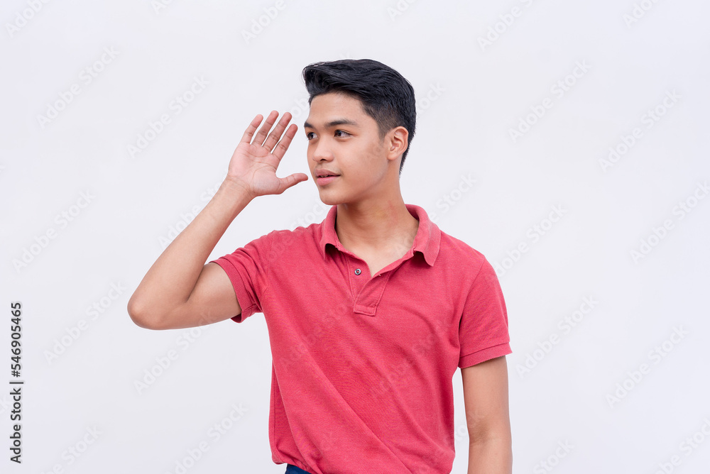 A young asian man hearing some nearby chitchat. Hand gesture on ear. Isolated on a white background. A young asian man hearing some nearby chitchat. Hand gesture on ear. Isolated on a white background.