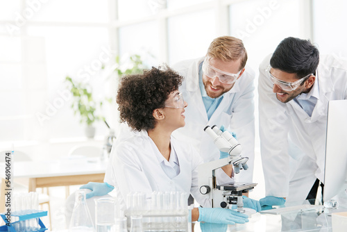 group of scientists working with a microscope to develop a vaccine against coronavirus .