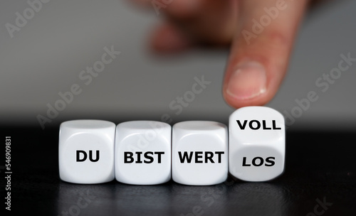 Hand dreht Würfel und ändert den Ausdruck 'du bist wertlos' in 'du bist wertvoll'. photo