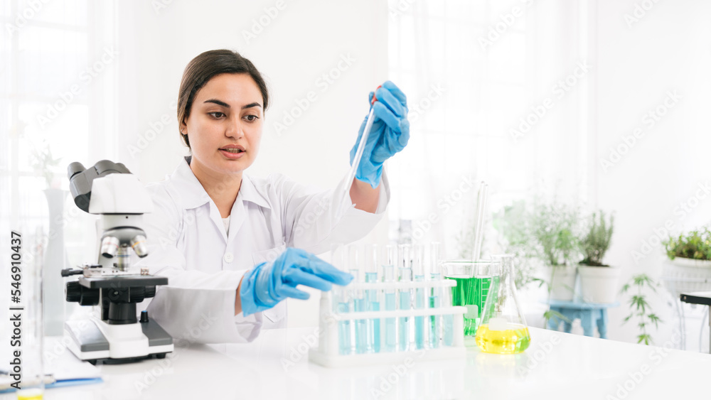 Middle East woman scientist researcher use a lab dropper to drip a substance into a test tube for analysis of liquids in the lab. Scientist working with a dropper and a test tube. Middle East woman scientist researcher use a lab dropper to drip a substance into a test tube for analysis of liquids in the lab. Scientist working with a dropper and a test tube.