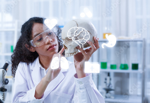 A professional female doctor in a white lab coat is examining the skull in the laboratory.