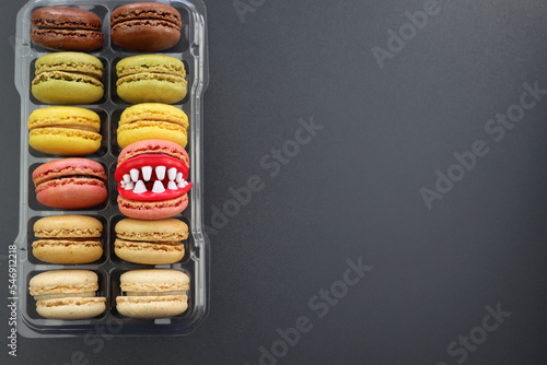  Fun macaroons with plastic teeth. Multicolored macaroons in clear packaging on a gray background