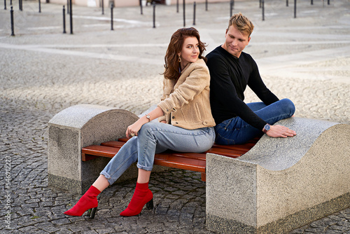 Obraz na płótnie Beautiful young couple sitting on a bench in the city during a romantic date w salonie
