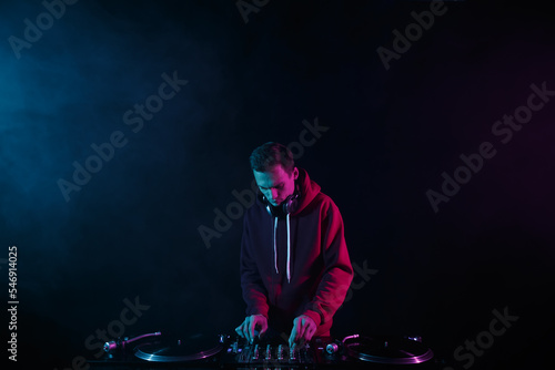 Hip hop dj plays set with vinyl records and sound mixer. Disc jockey playing music with turntables in night club