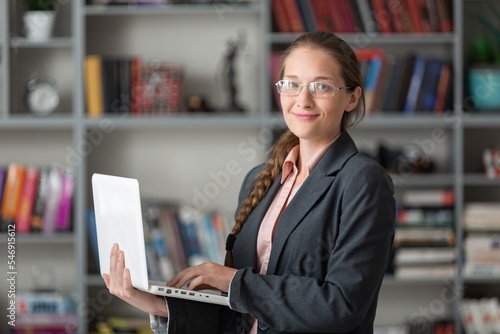 Young girl studying alone in library, in glasses with laptop.