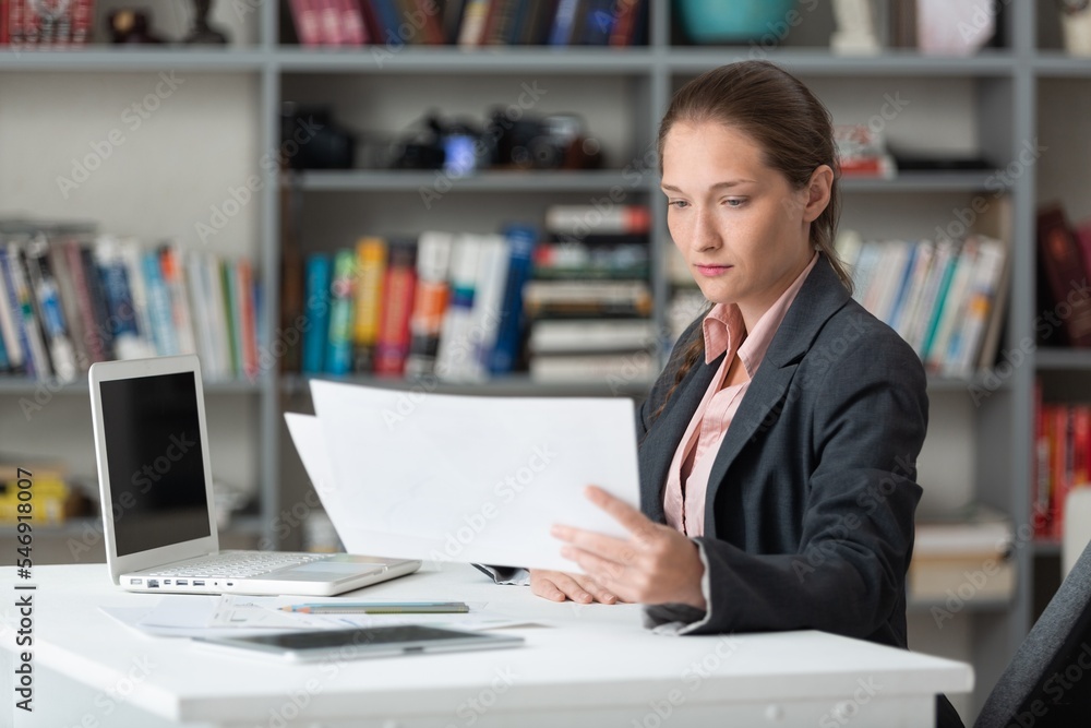 Young business woman working with paper documents, in office. Young business woman working with paper documents, in office.