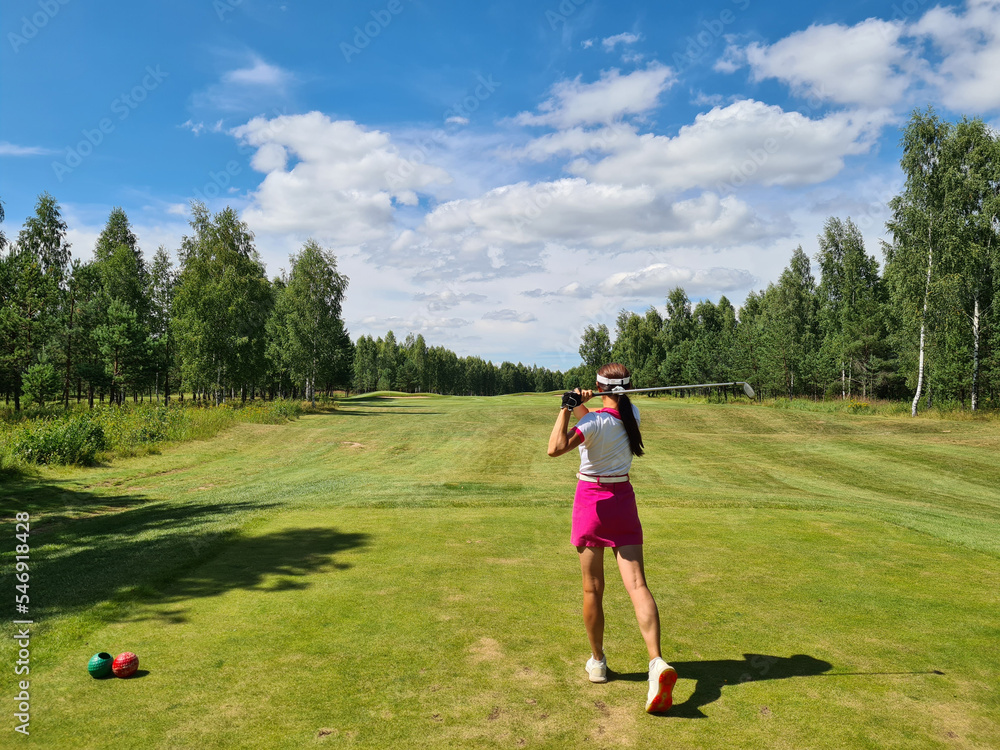 Female golfer swings golf club on golf course Female golfer swings golf club on golf course