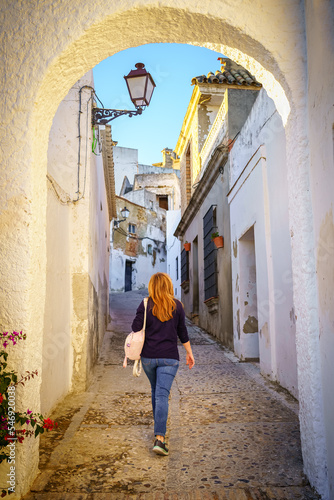 Woman walking down a narrow street in a village with white houses in Andalucia, Cadiz.