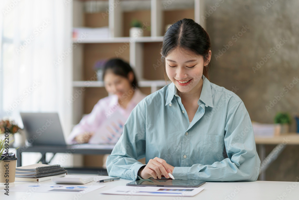 Beautiful young Asian business woman using tablet to work smiling and enjoying her job. Beautiful young Asian business woman using tablet to work smiling and enjoying her job.