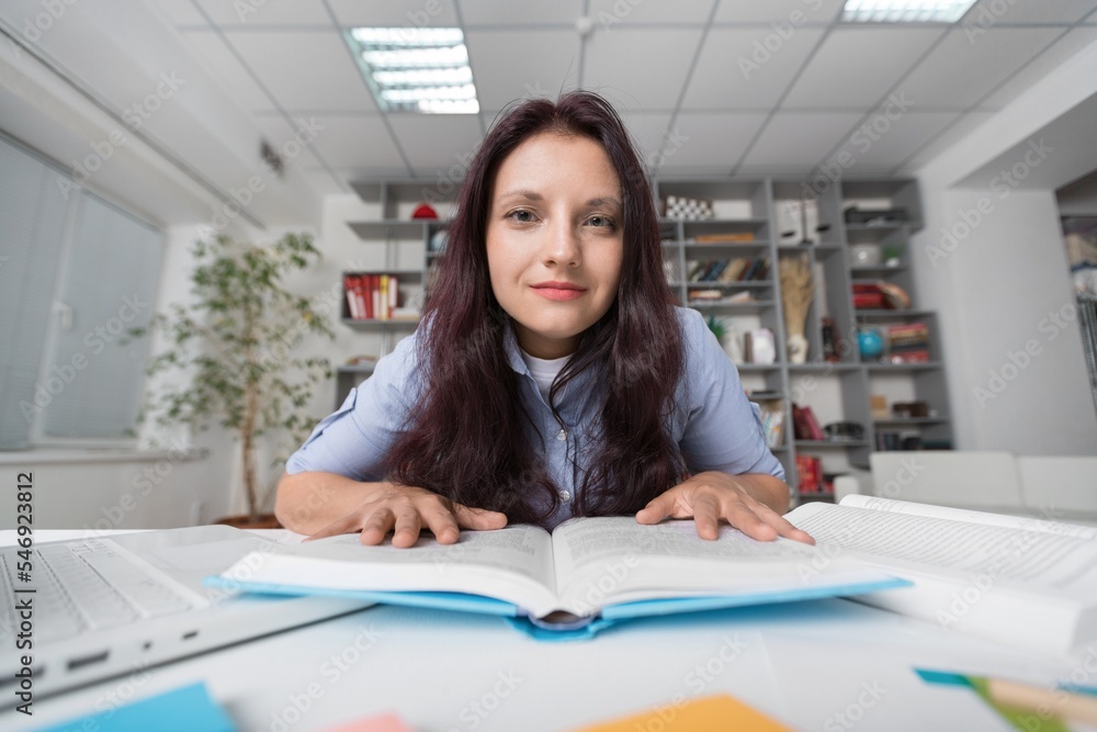 Young woman sitting at table and working with books Young woman sitting at table and working with books