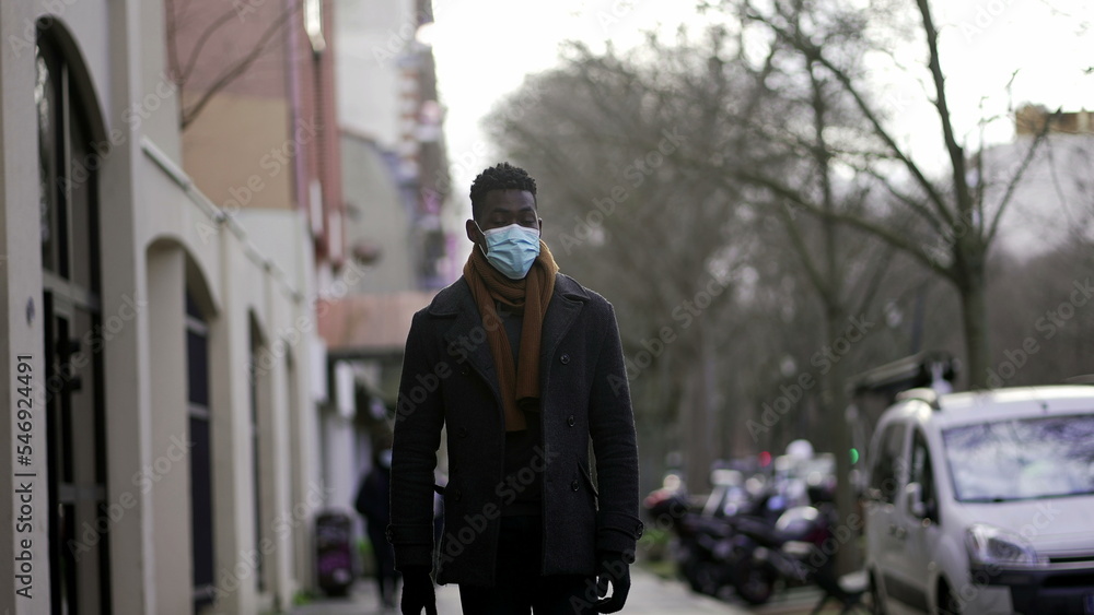 Fototapeta premium Elegant African man walking in slow-motion wearing face mask prevention against pandemic