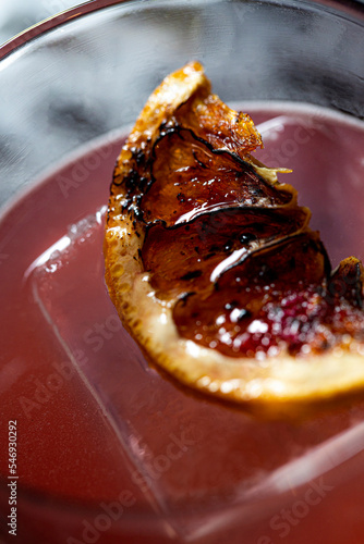 Torched dehydrated orange slice for craft cocktail garnish garnish on large clear ice cube