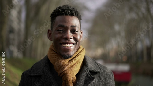 Confident young black African man walking outside in nature park during winter season