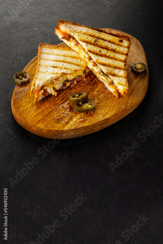 Fried grilled white bread club sandwich with jalapeno on wooden board.