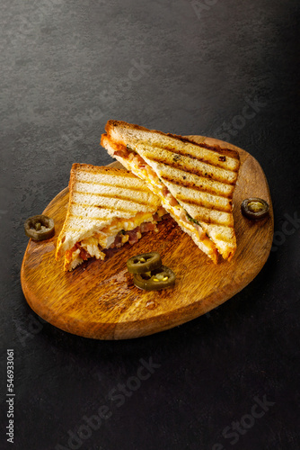 Fried grilled white bread club sandwich with jalapeno on wooden board.