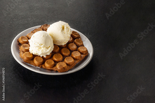 Hong Kong chocolate bubble waffle with ice cream on dark background with copy space.