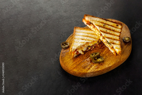 Club sandwich with jalapeno on wooden board.