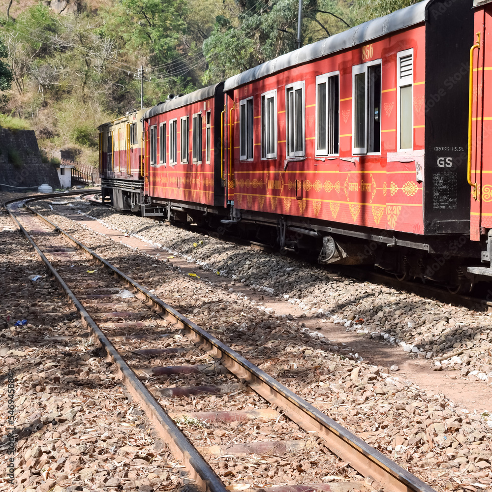 Obraz premium Toy Train moving on mountain slopes, beautiful view, one side mountain, one side valley moving on railway to the hill, among green natural forest. Toy train from Kalka to Shimla in India, Indian Train