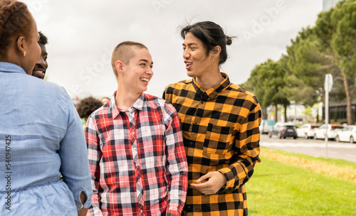 Two young people of non binary gender enjoy with other friends in a public park. photo