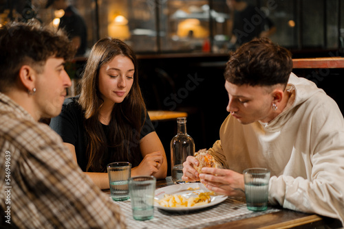 a group of friends chatting at a table in a restaurant  eating a burger and french fries