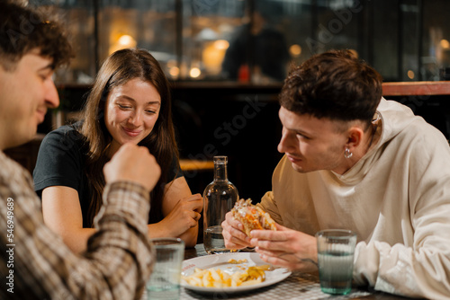 a group of friends chatting at a table in a restaurant  eating a burger and french fries