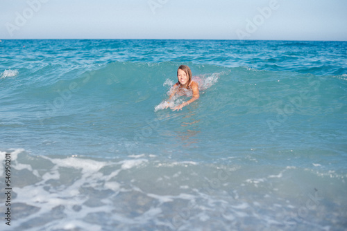 Little girl in the spray of waves at sea on a sunny day