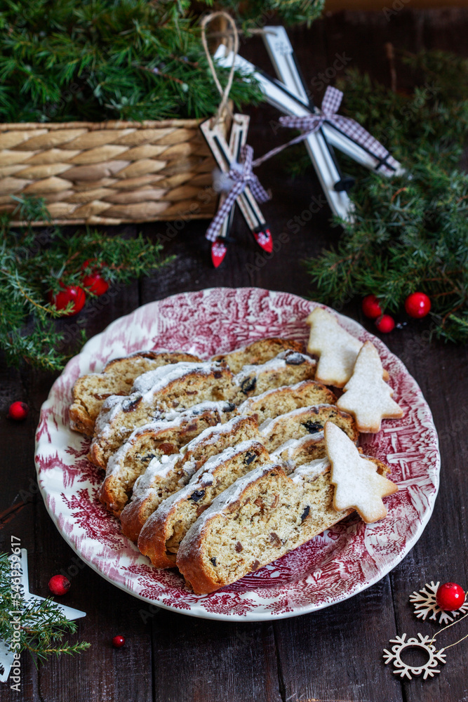 Christmas stollen with dried fruits, nuts and spices, Christmas decorations on a dark wooden background. Rustic style.