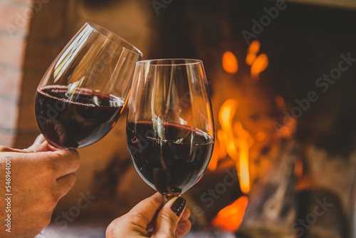 Casal brindando com vinho tinto em lareira no inverno photo