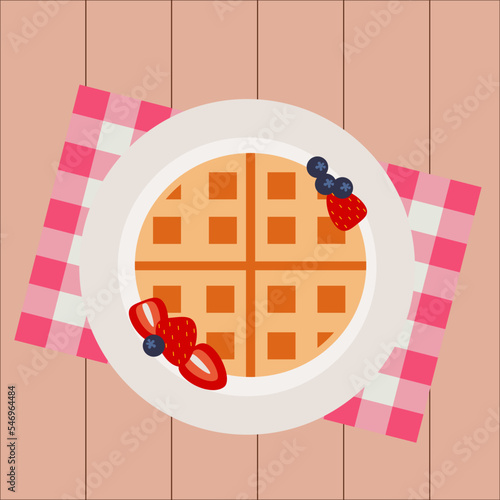 Simple flat sweet round  brown waffle with blueberries and strawberries on a white plate and traditional red napkin and wooden table background