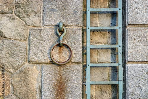 Large metal ring for parking yachts and boats and a staircase on a stone wall on the embankment of the Vltava River in Prague.