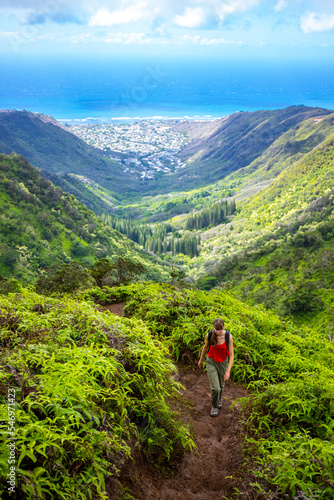 hiker girl enjoys the panorama of oahu island and honolulu in hawaii islands while climbing wiliwilinui ridge trail; hiking on green mountains in hawaii, holidays in hawaii