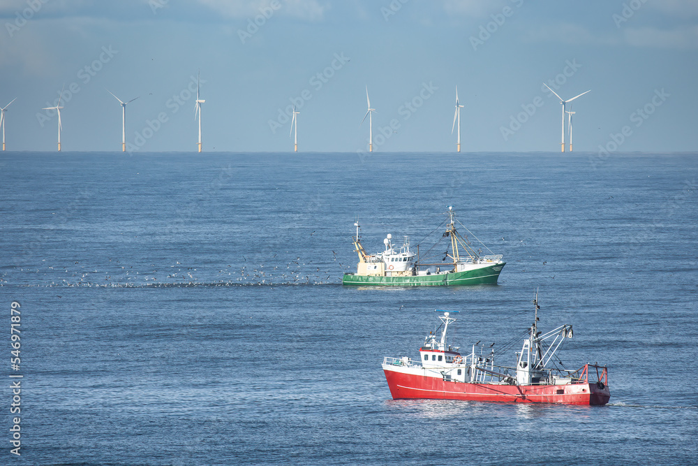 Two cutters passing each other in the North sea close with wind turbines of a windfarm in the background