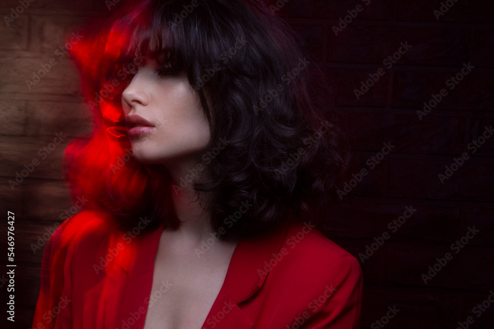 Fashion photo of young woman with makeup and hairstyle, wear red suit, with closed eyes, red neon studio light. Fashion photo of young woman with makeup and hairstyle, wear red suit, with closed eyes, red neon studio light.