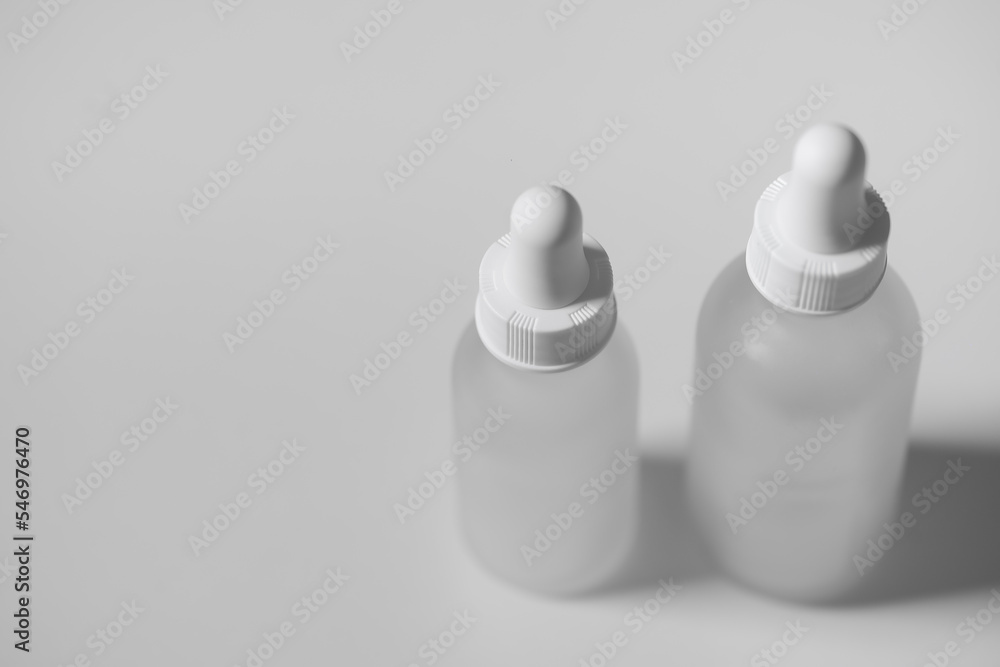 Top view of two empty white translucent glass dropper vials beside each other. Different-sized bottles on white surface. Horizontal beauty and lifestyle background, mockup, and copy space.