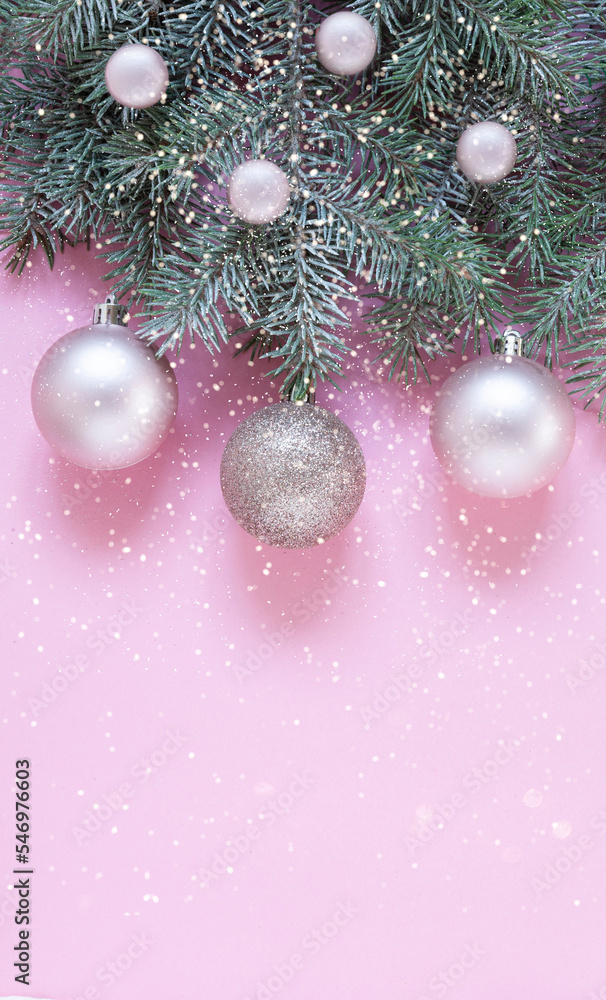 Fototapeta premium Christmas and New Year festive composition with snow fir tree branches, and gentle pink Christmas balls on the pink background