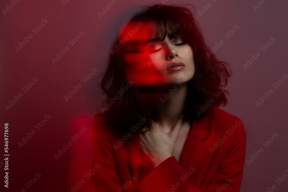 Portrait of young woman with makeup and hairstyle, wear red suit, with closed eyes, red studio light and effects. Portrait of young woman with makeup and hairstyle, wear red suit, with closed eyes, red studio light and effects.