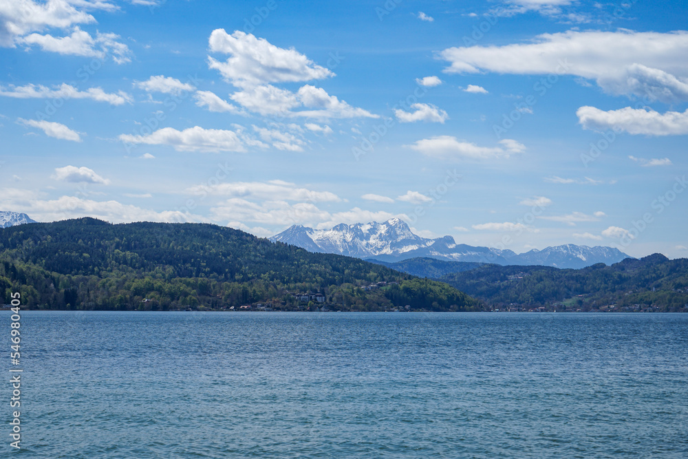 Beautiful and idyllic lake woerthersee in austria. Steep snowy mountains in the background. Klagenfurt, Carinthia, Austria.