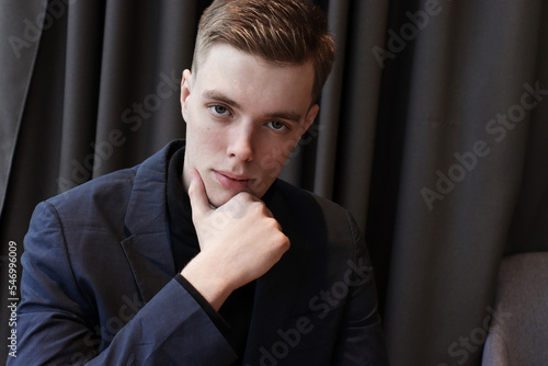 portrait of a handsome young man in a classic suit sitting at a table. 