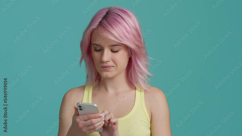 Student closing eyes and crosses fingers, thinking about cherished desire or wish for more likes in blog. Girl with pink hair with smartphone cautiously looking around, thinking about tough decision Student closing eyes and crosses fingers, thinking about cherished desire or wish for more likes in blog. Girl with pink hair with smartphone cautiously looking around, thinking about tough decision