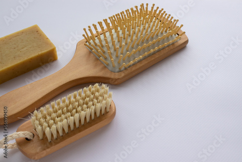 Beauty accessories wooden comb  nail brush  soap bar on white background. Modern paddle hair brush on table. Top view  flat lay  copy space.  