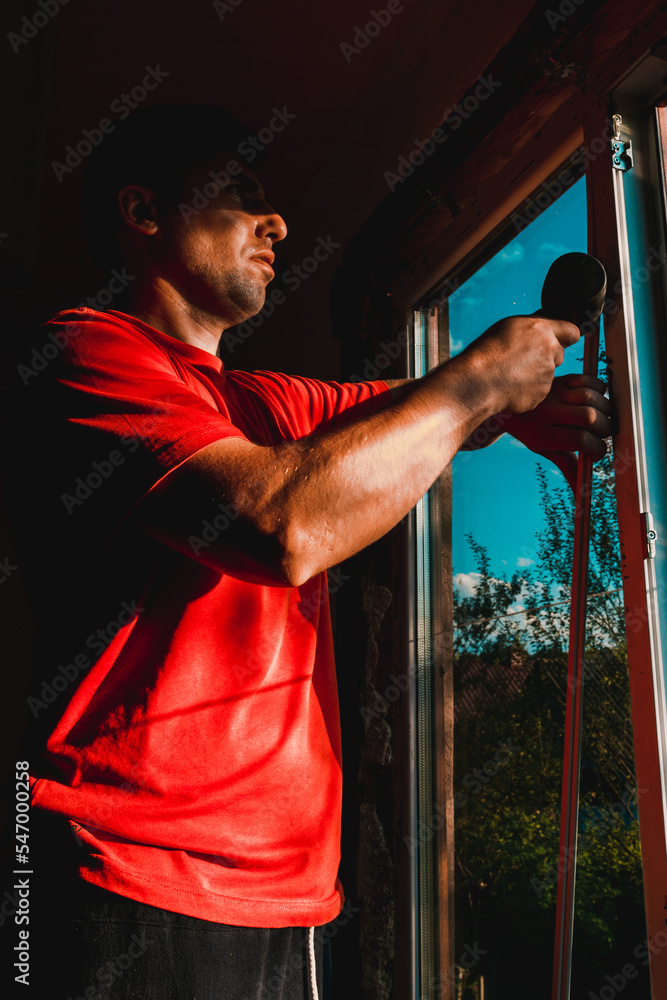 the man assembles the window, installs the double-glazed windows and fastens the corner posts with a rubber hammer to hold the glass.